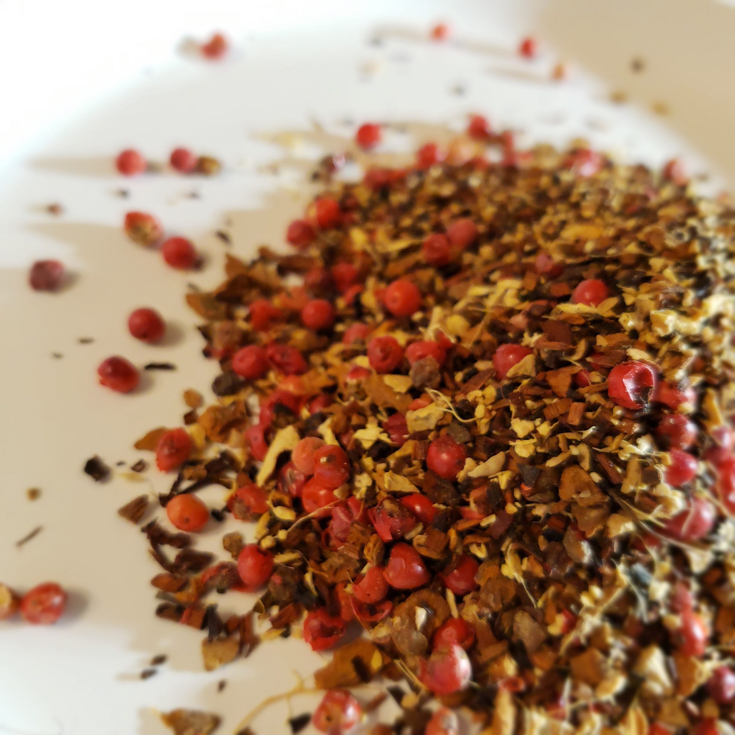 image of loose leaf tea on a white plate; includes honeybush, peppercorn, ginger and cinnamon