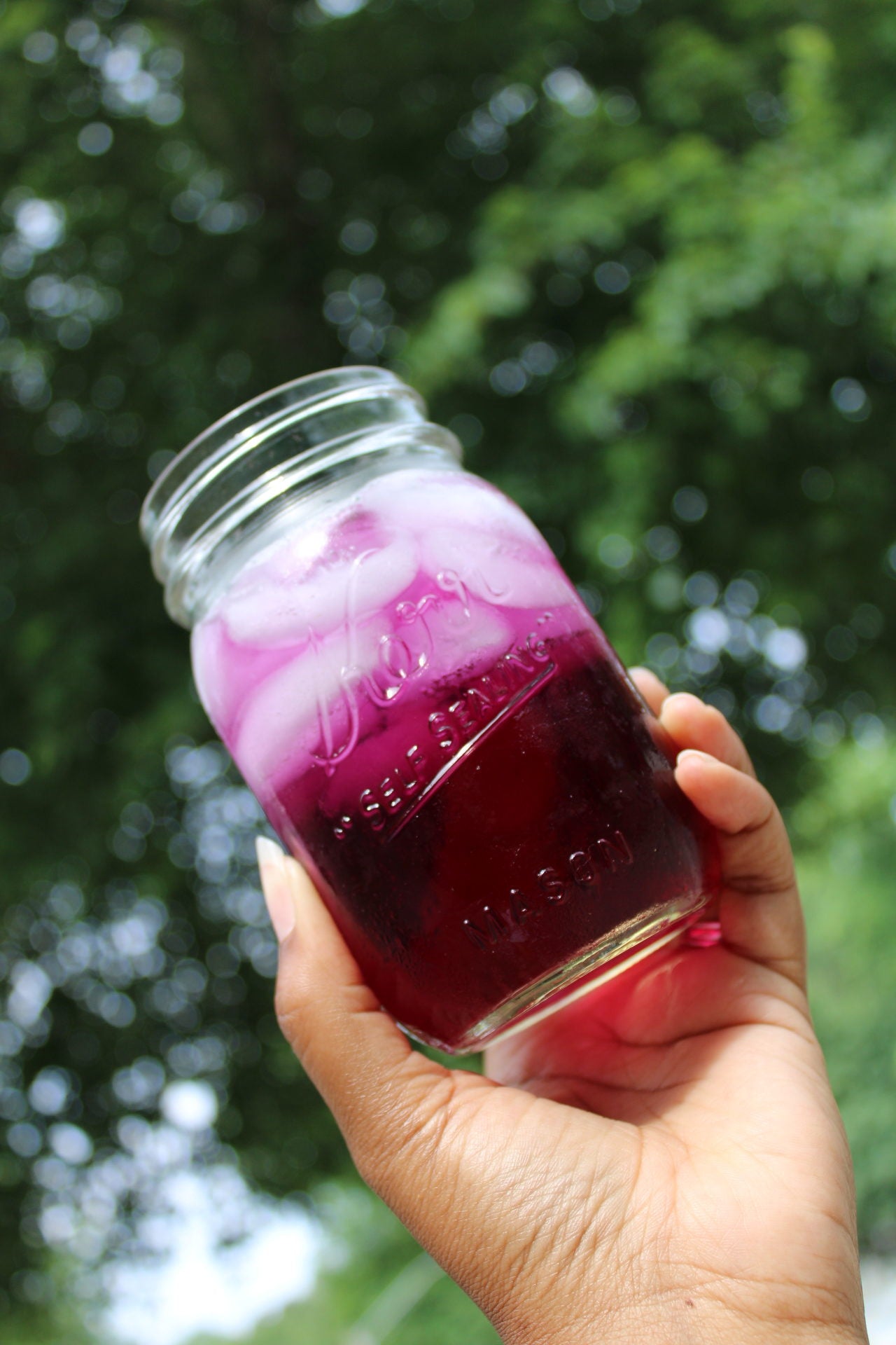 ID: Cold glass of iced Purple Reign tea in a small mason jar with ice.