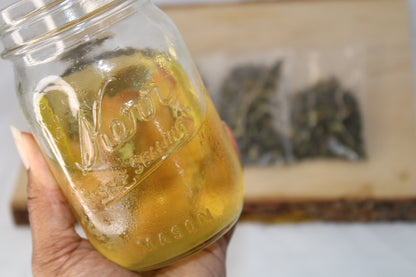 ID: picture of small mason jar filled with iced green tea and iced tea pouches out of focus in the background.